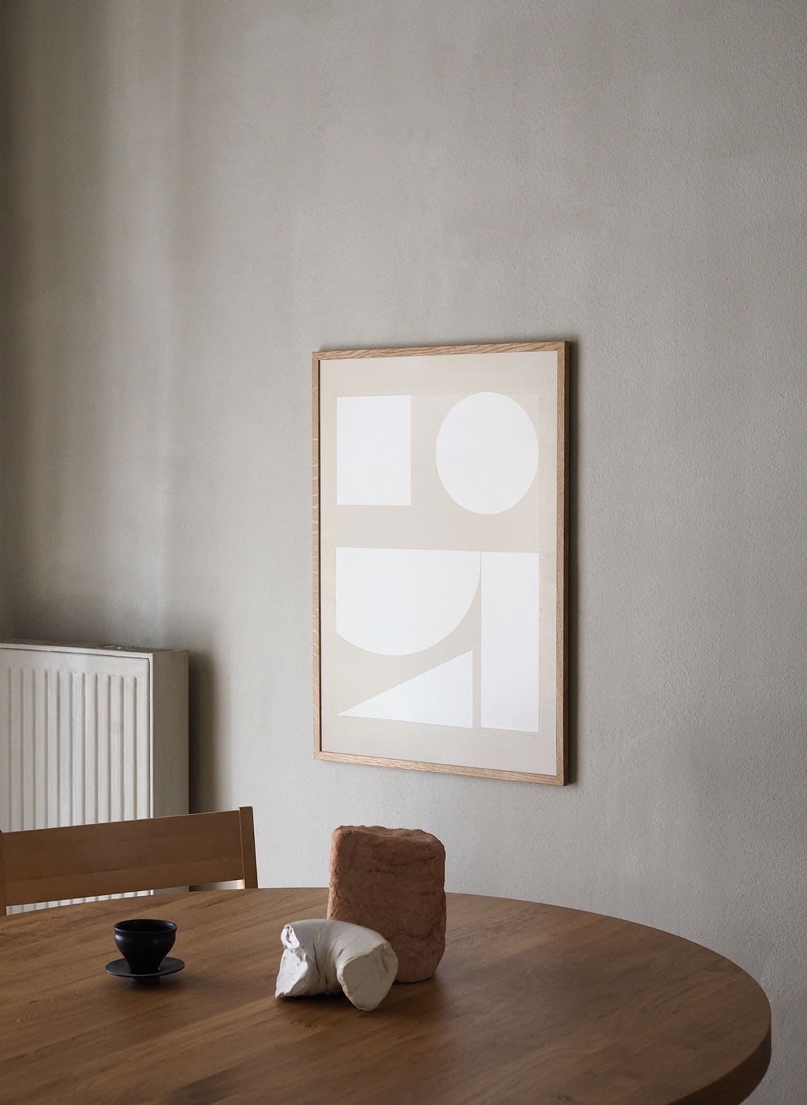 Framed minimalistic poster hanging above dining table by Atelier Cph