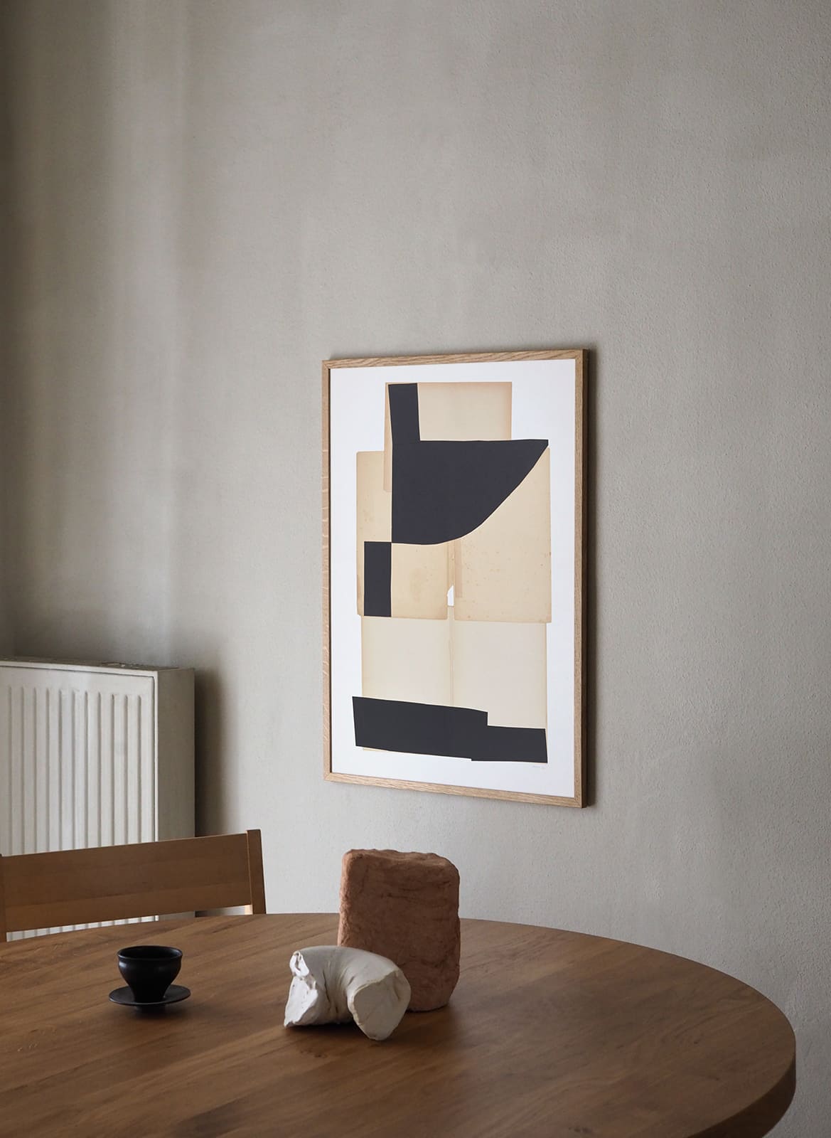 Framed minimalistic poster hanging above dining table by Atelier Cph