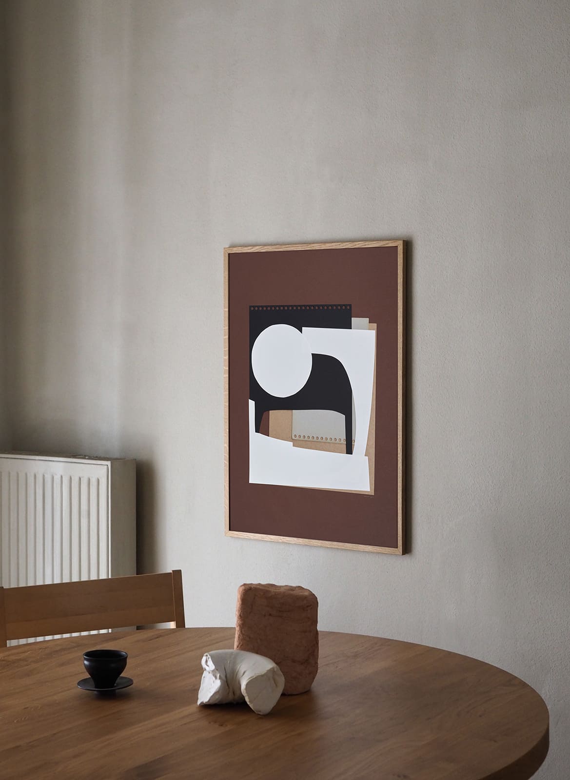 Framed minimalistic poster hanging above dining table by Atelier Cph
