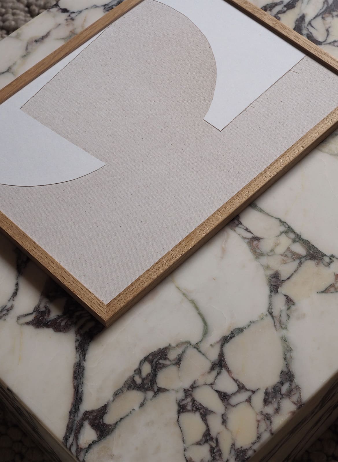 Framed white on white poster laying on a marble table by Atelier Cph