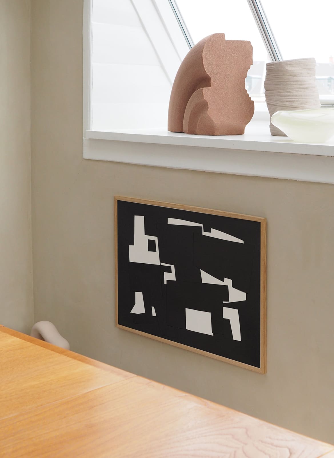 Framed abstract black poster hanging behind a table by atelier cph