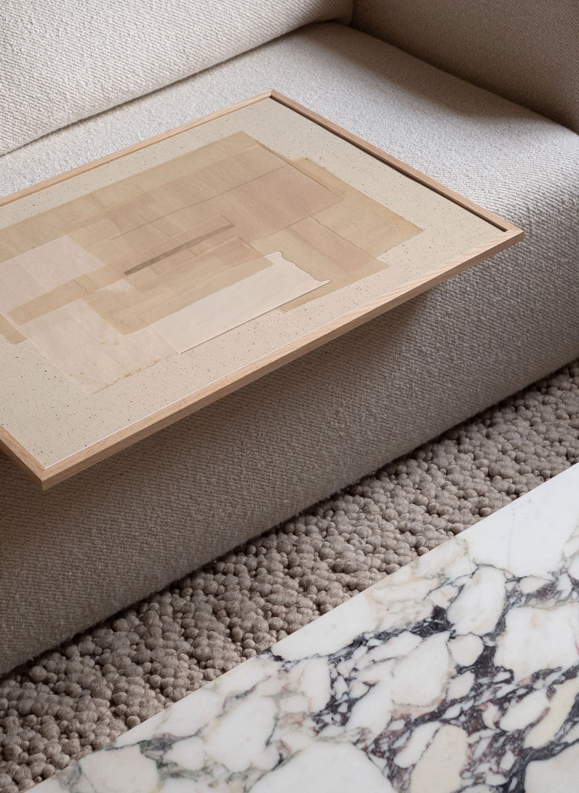 Beige minimalistic poster laying on a couch by atelier cph