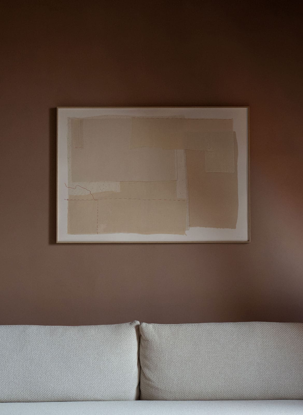 Framed beige poster hanging above a couch by atelier cph