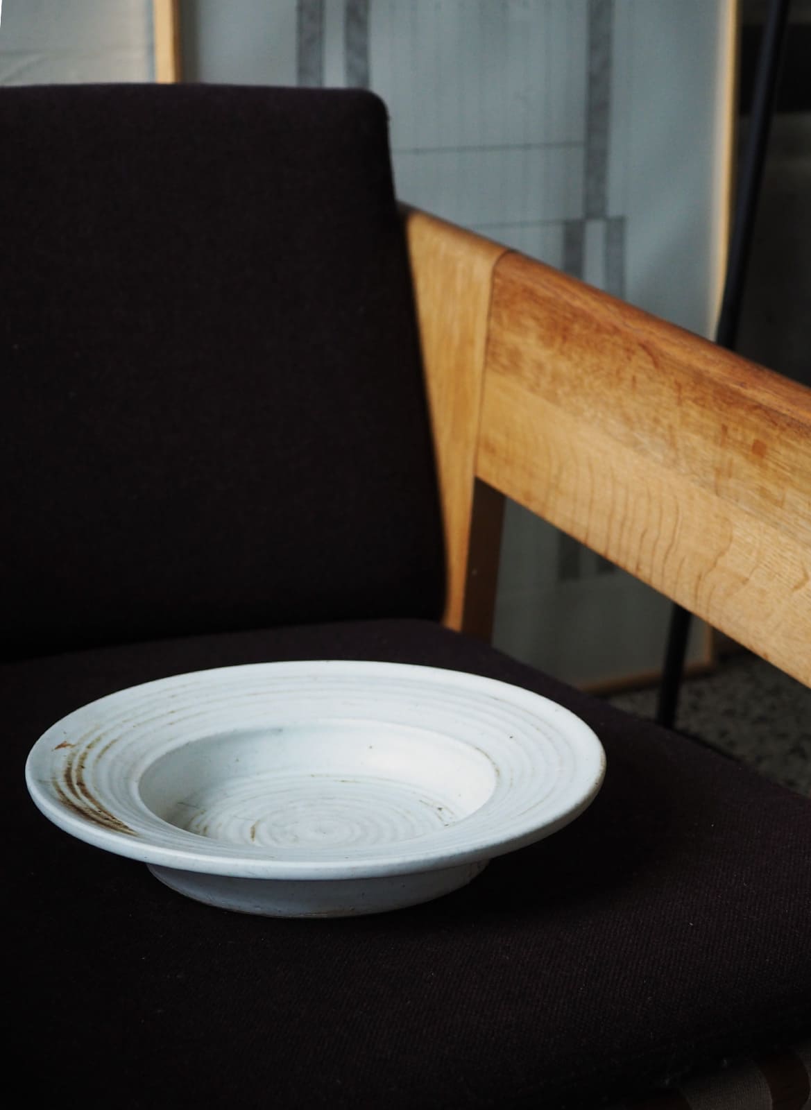 White ceramic dish with brown glaze details standing on a chair