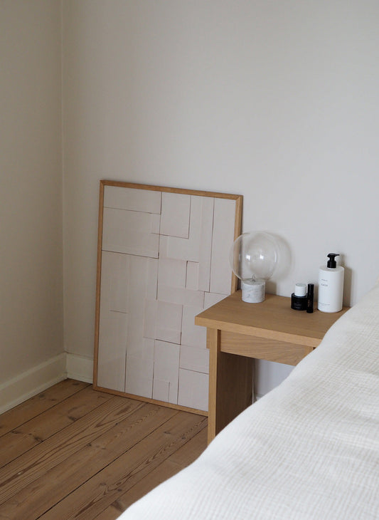 Minimalist abstract print showing paper layered details in a wooden frame behind a minimalistic Japanese table