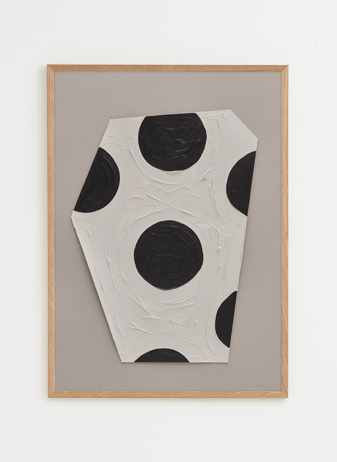 Abstract art piece with black and white circles on a gray background, framed in wood.