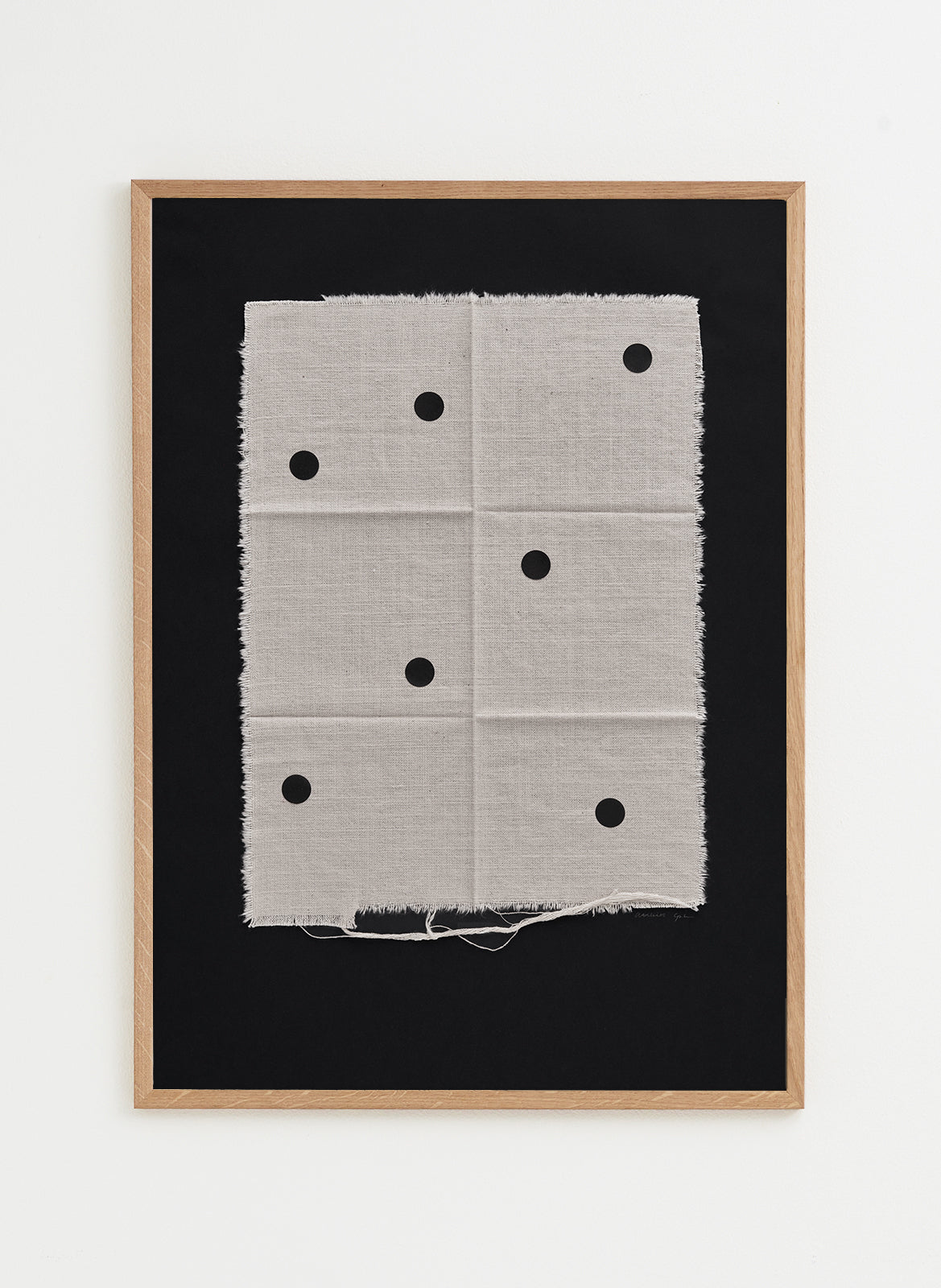 Framed artwork with a black background and white fabric with black dots