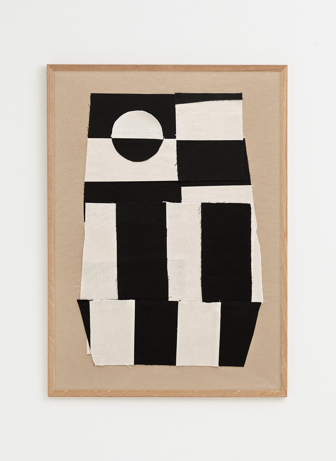 Framed abstract artwork with black and white geometric design on a beige background