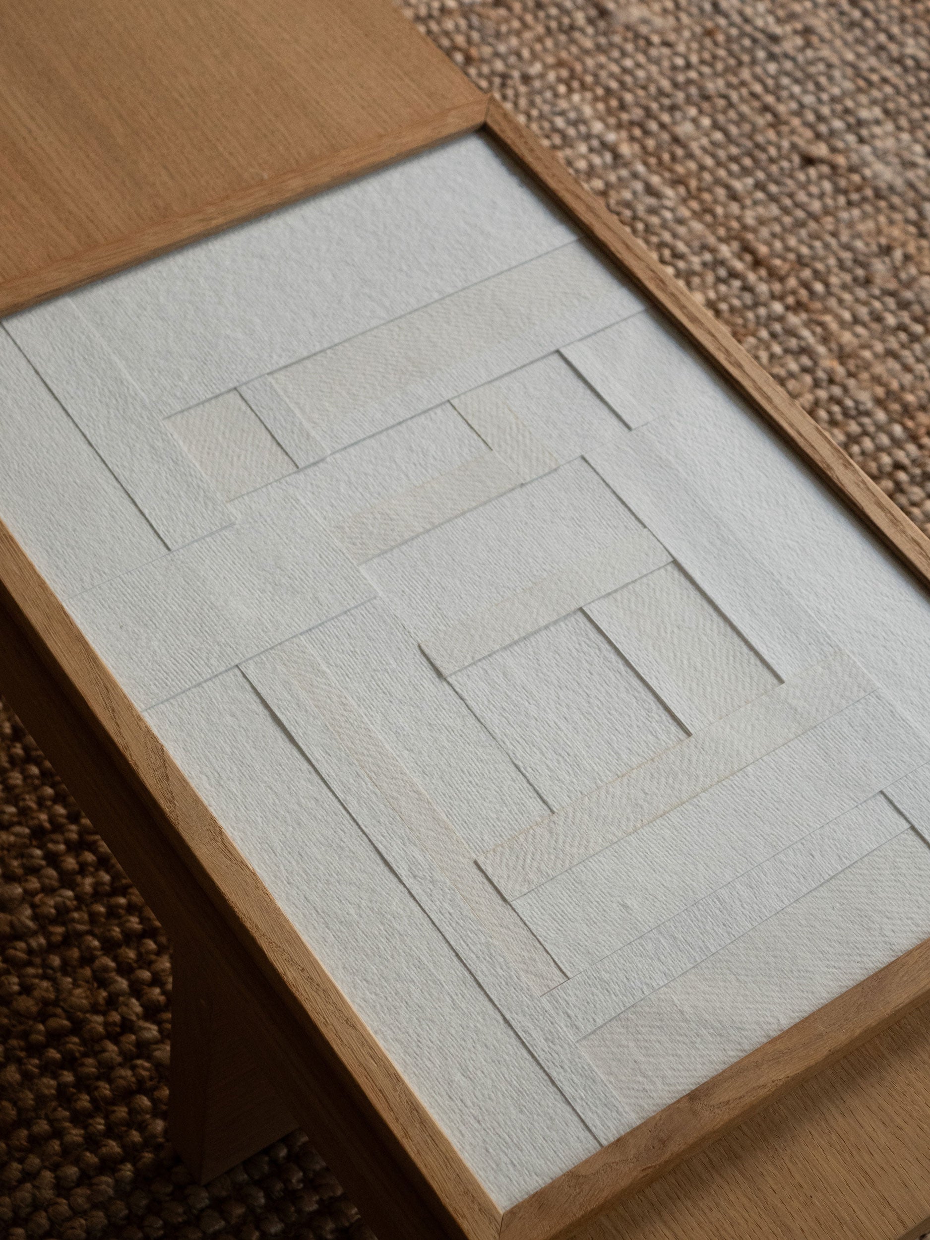 Minimalist white paper collage with layered geometric shapes in a light oak frame, created as a limited edition by Atelier Cph.