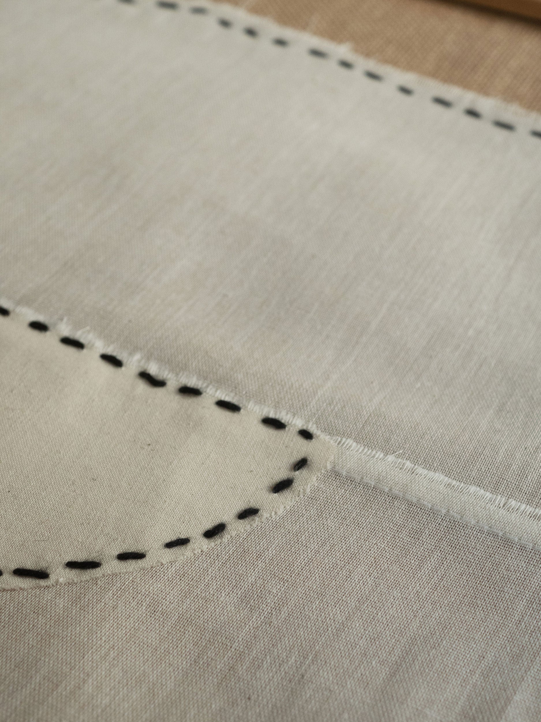 Close-up of beige fabric with black stitching by atelier cph