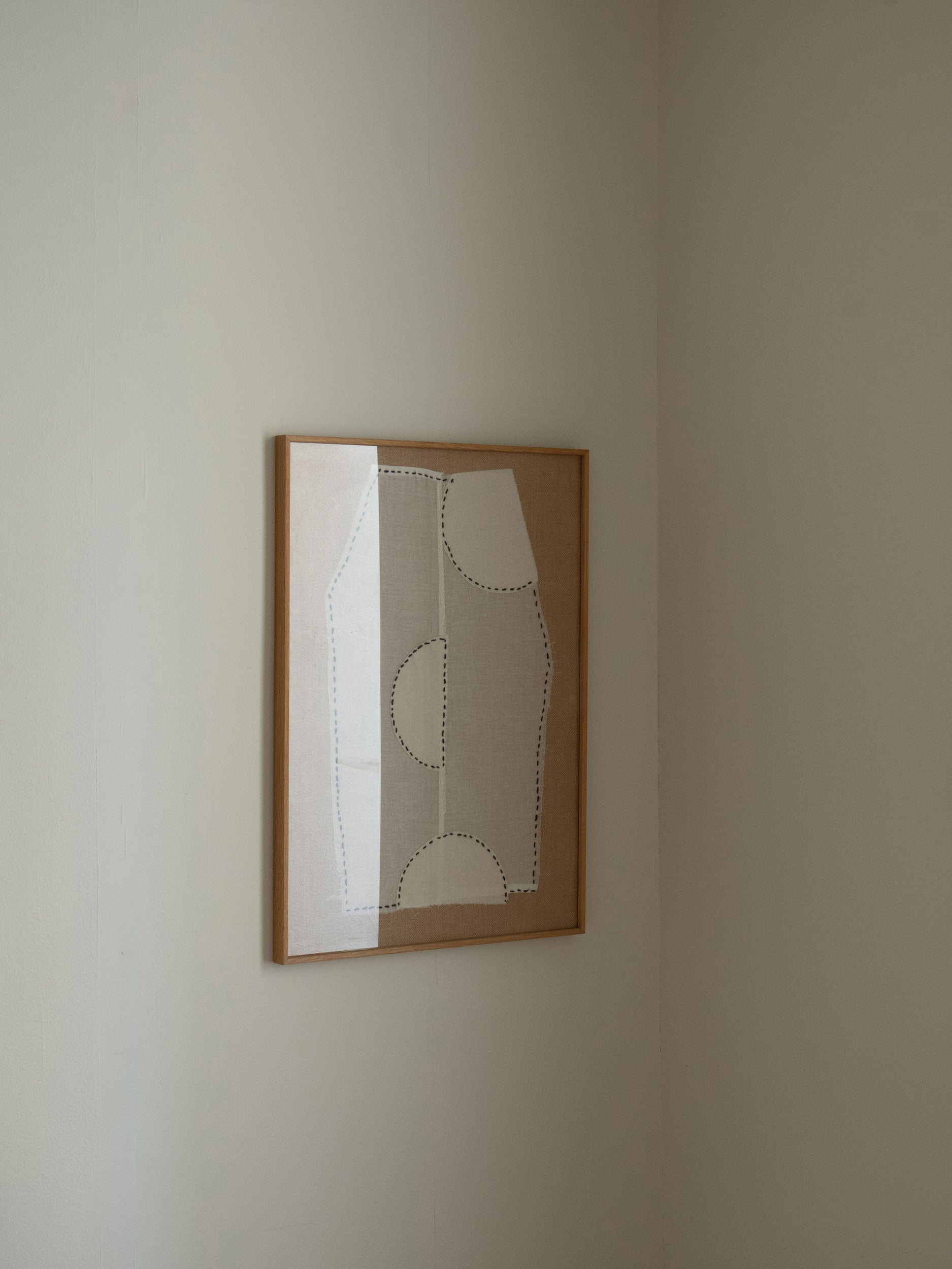 Minimalist textile artwork with white fabric, black stitched lines and curved shapes on a sand-coloured fabric background, framed in oak, created as a limited edition by Atelier Cph.