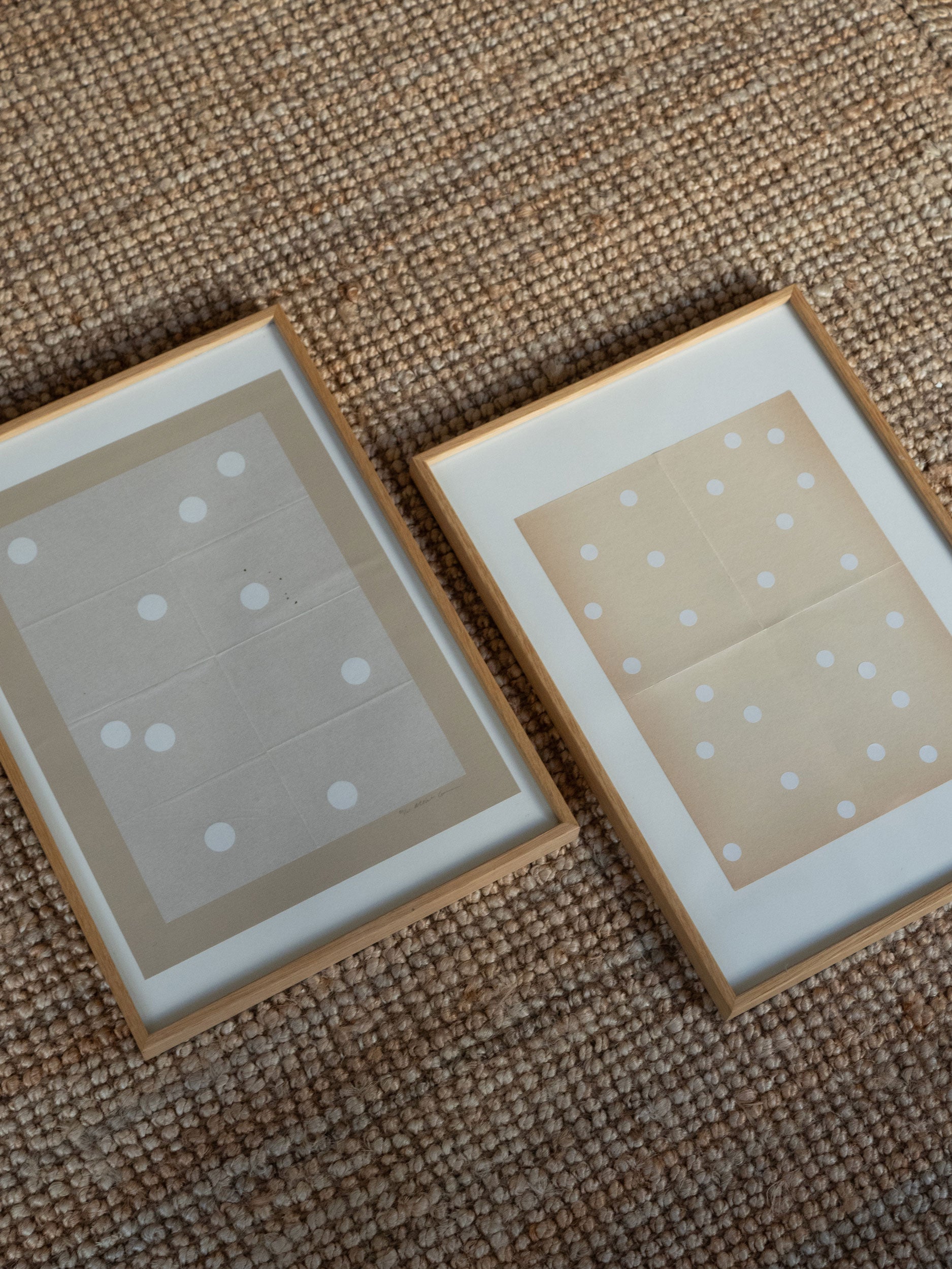 Two small framed pictures with polka dot designs by Atelier Cph in oak frames laying on a textured surface