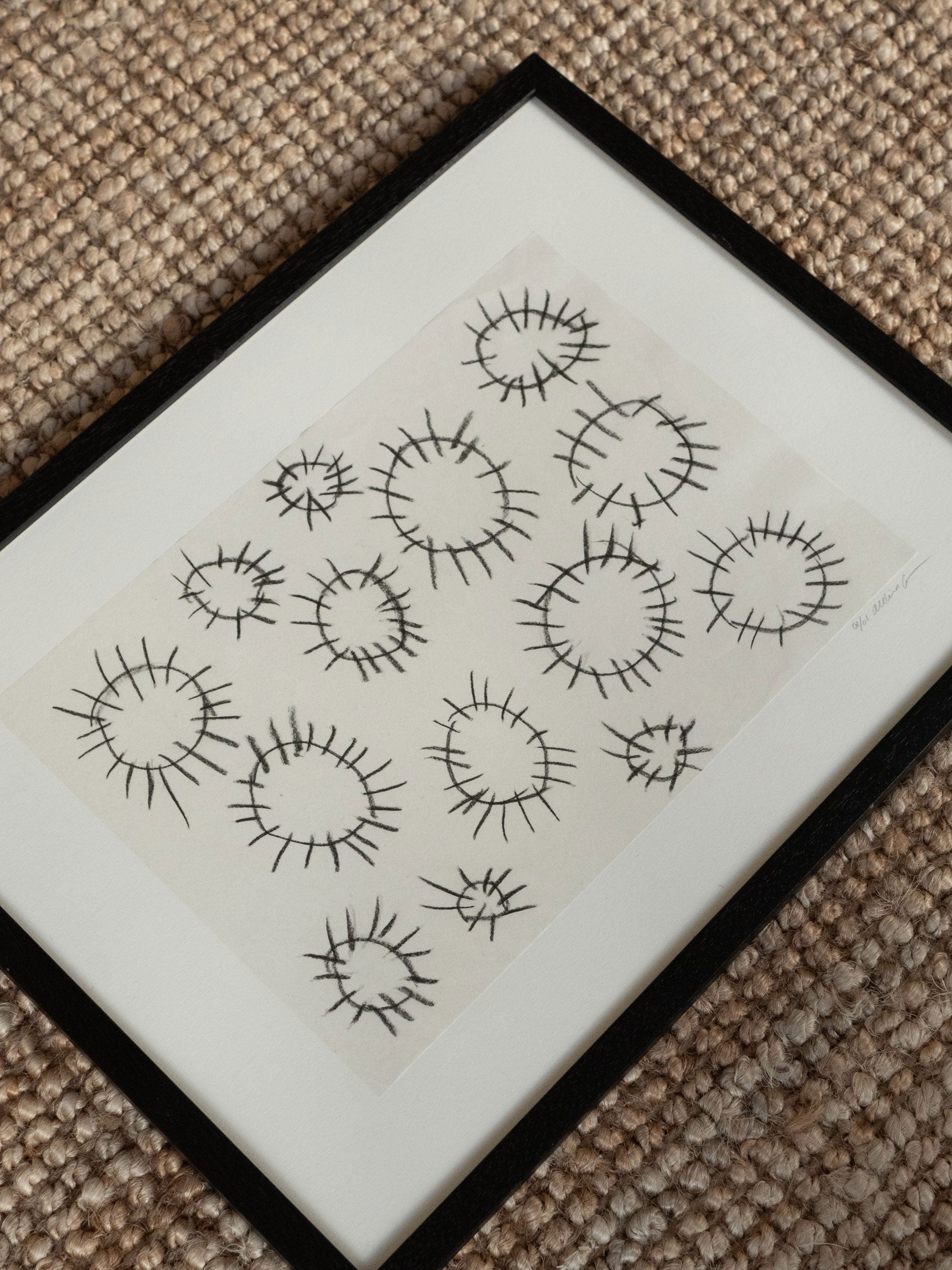 Minimalist artwork with hand-drawn black circular motifs on textured paper, framed in black wood, created as a limited edition by Atelier Cph.