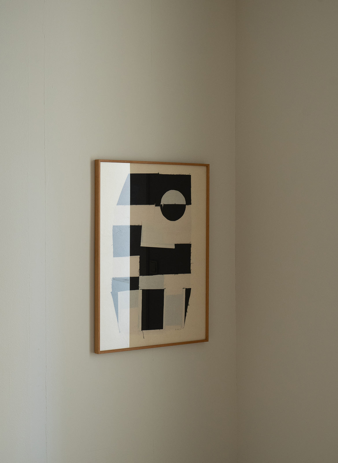 Black sewn geometric shapes on a white background in a wooden frame by atelier cph on a plain wall