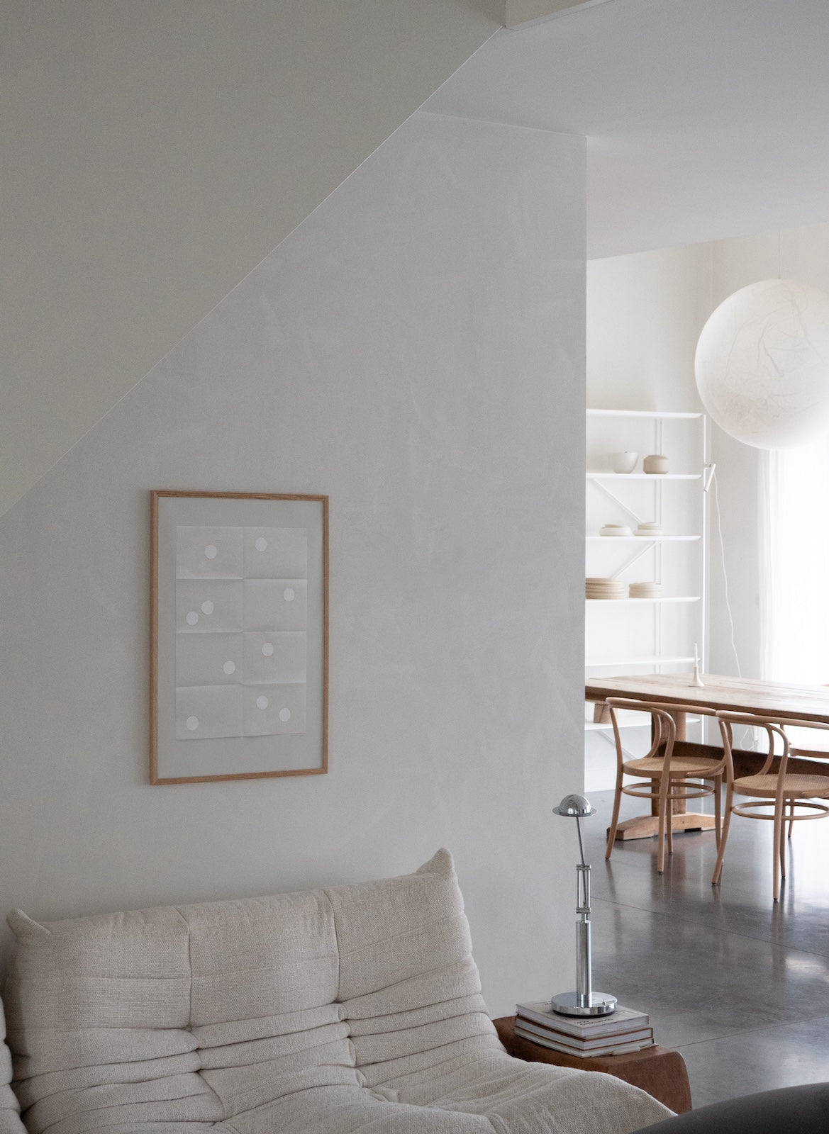 Modern living room with a sofa, lamp, and framed artwork on a white wall.