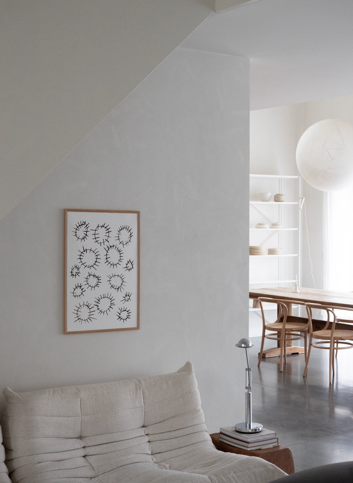 Modern living room with a sofa, wall art, and a view into another room.