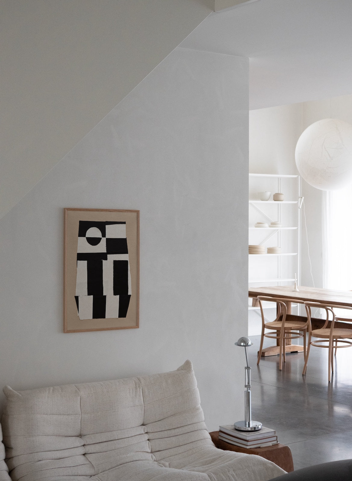 Modern living room with abstract art on the wall, sofa, and lamp.
