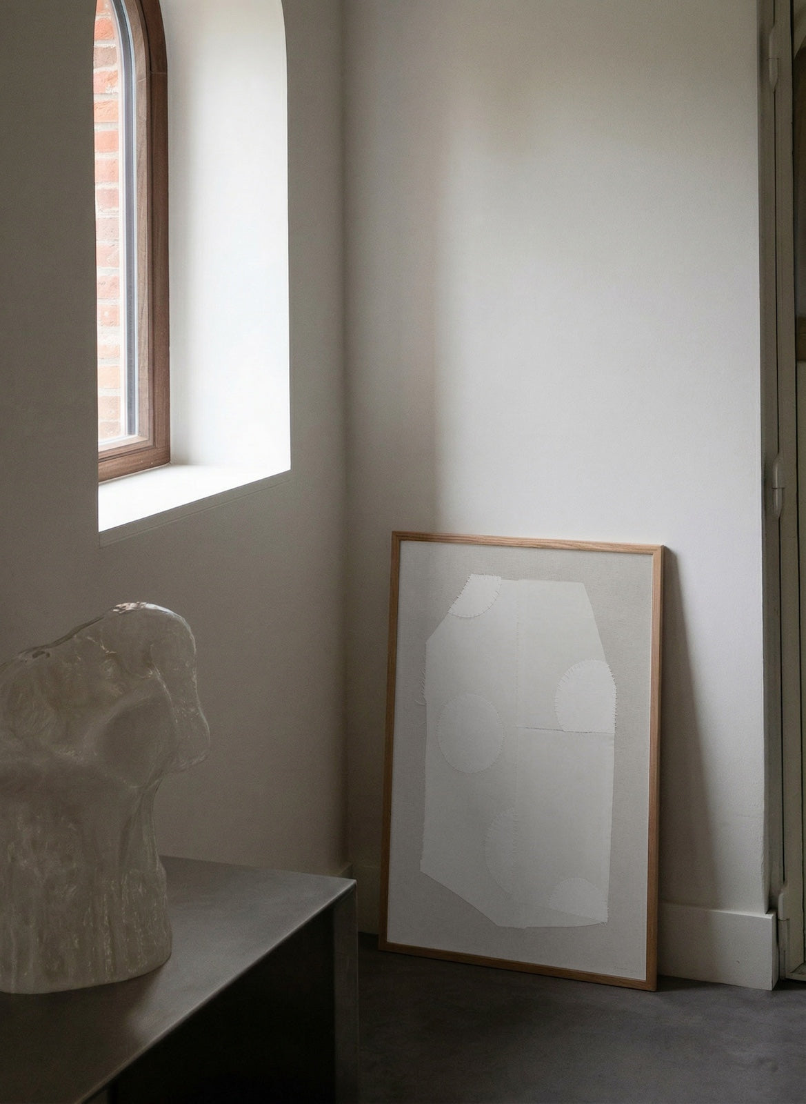 Framed abstract art leaning against a wall next to a window