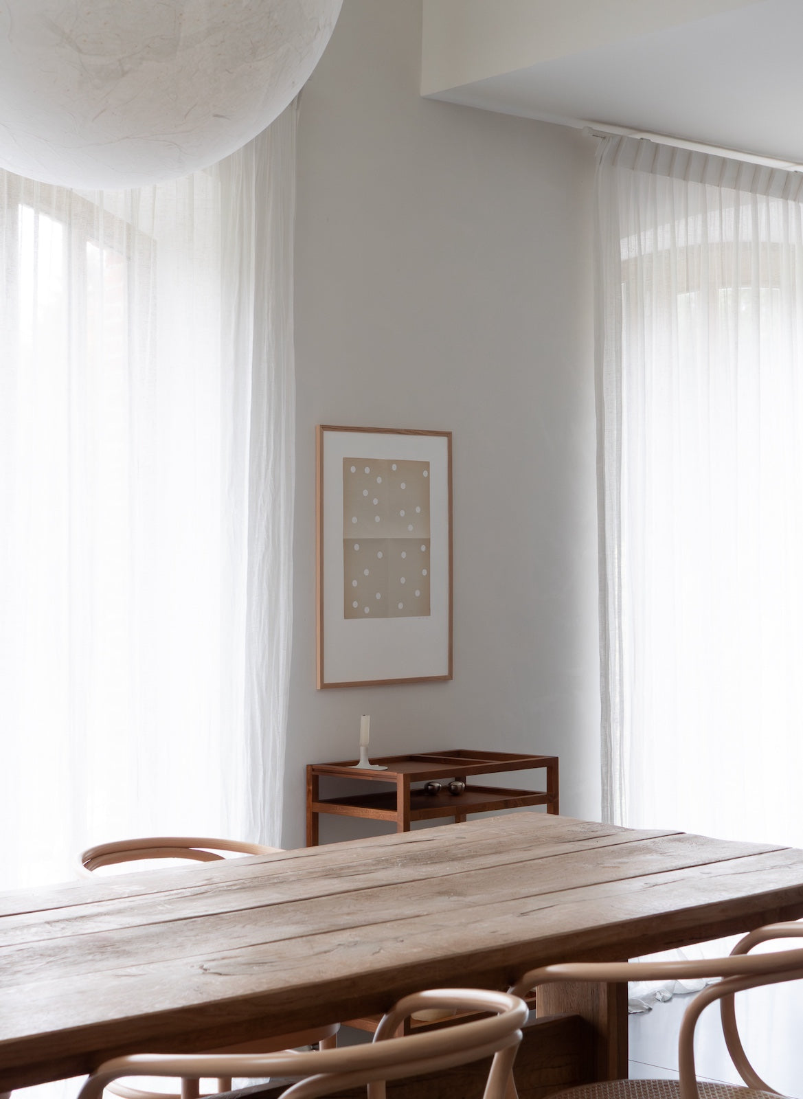 Modern dining room with wooden table and chairs, framed artwork on the wall.