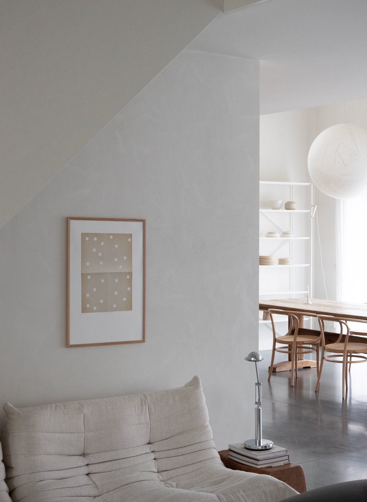 Modern living room with a sofa, lamp, and framed picture on a white wall.
