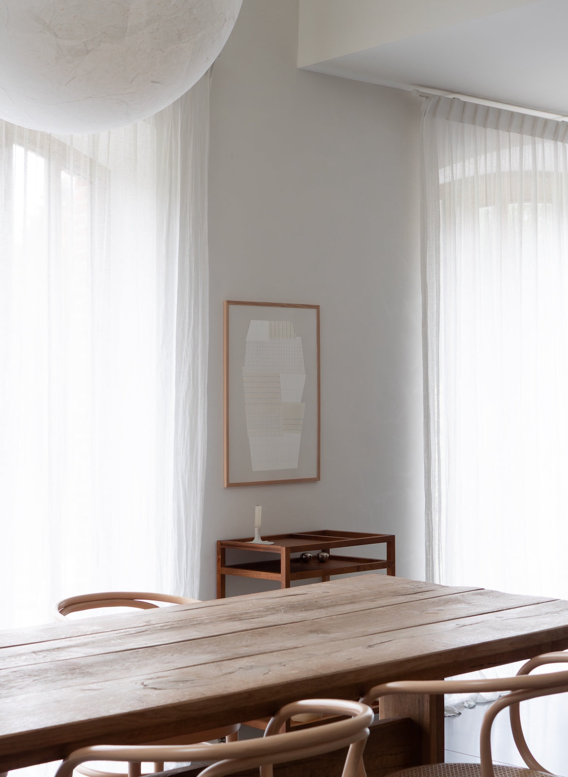 Modern interior with wooden table and chairs, framed abstract art on the wall.