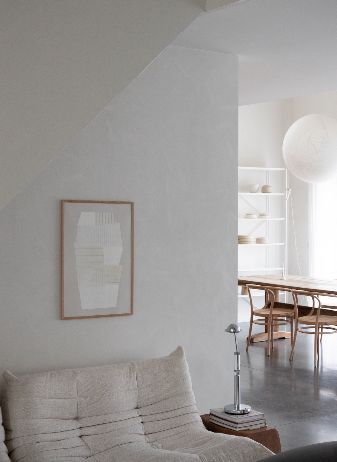 Modern living room with a sofa, lamp, and abstract art on a white wall.