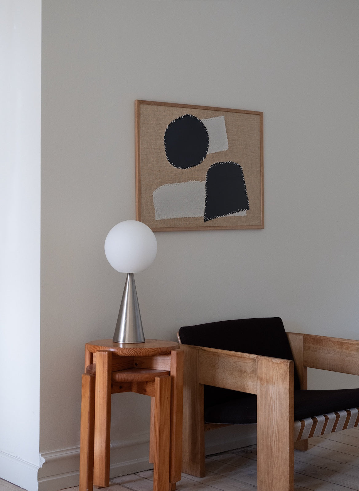 Modern interior with wooden chair, side table, and abstract art on the wall.