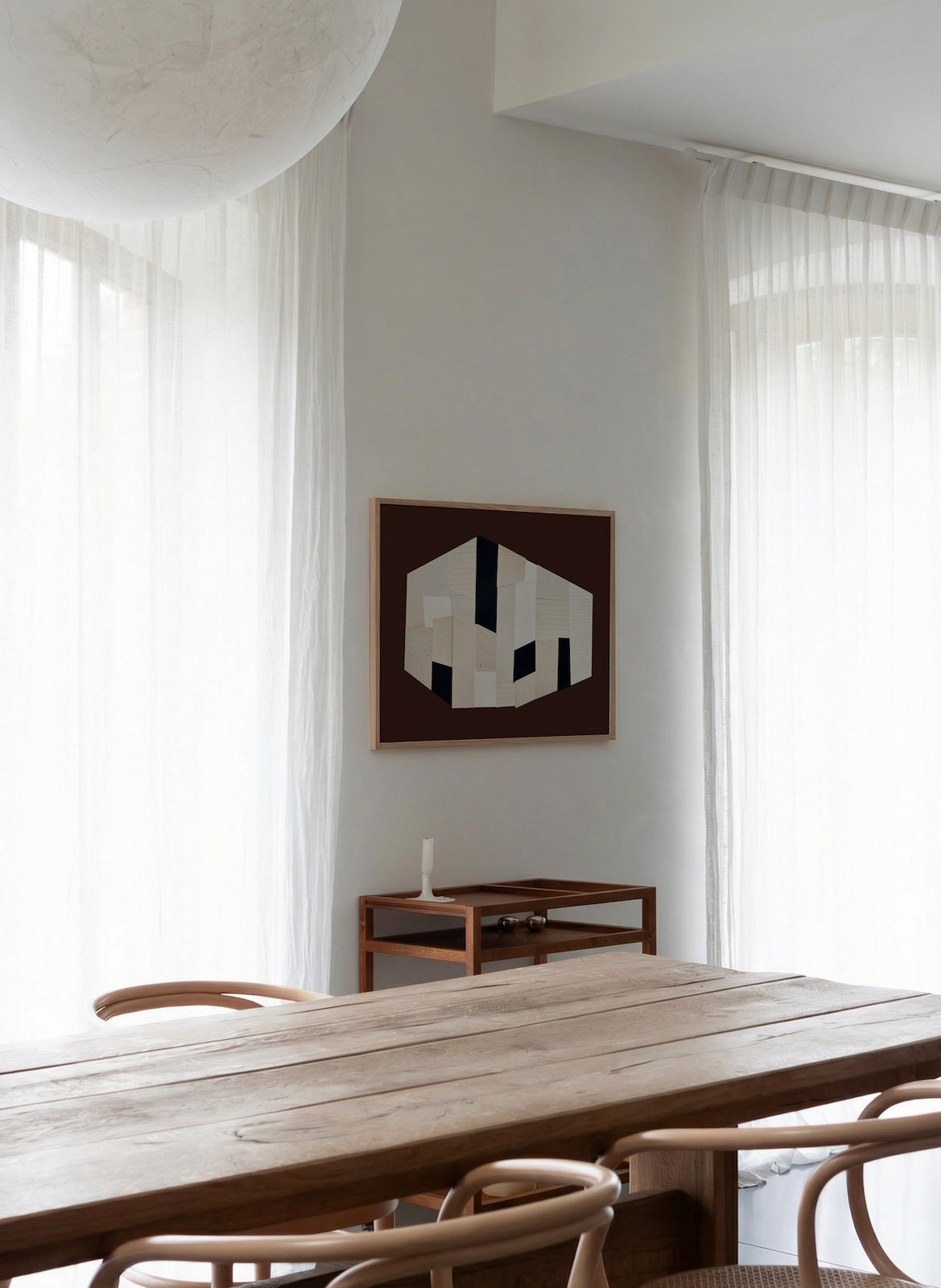 Modern dining room with wooden table and chairs, abstract art on the wall.