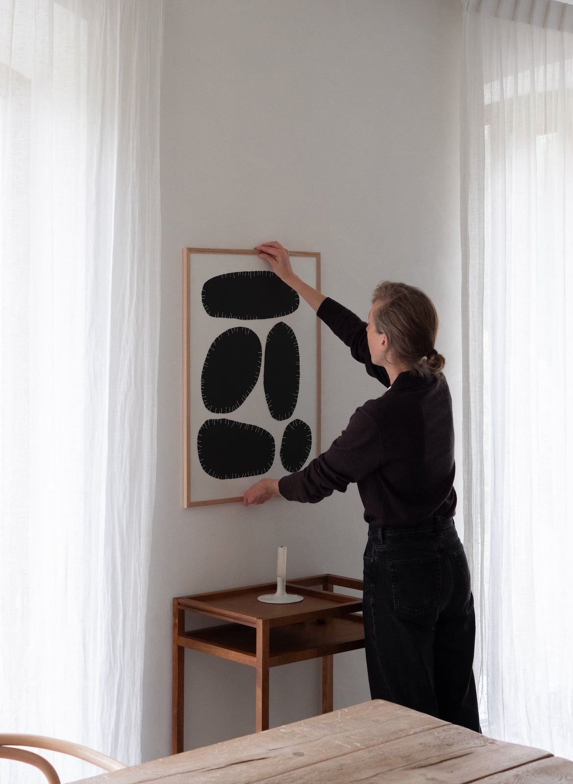 Person hanging a framed abstract artwork on a wall