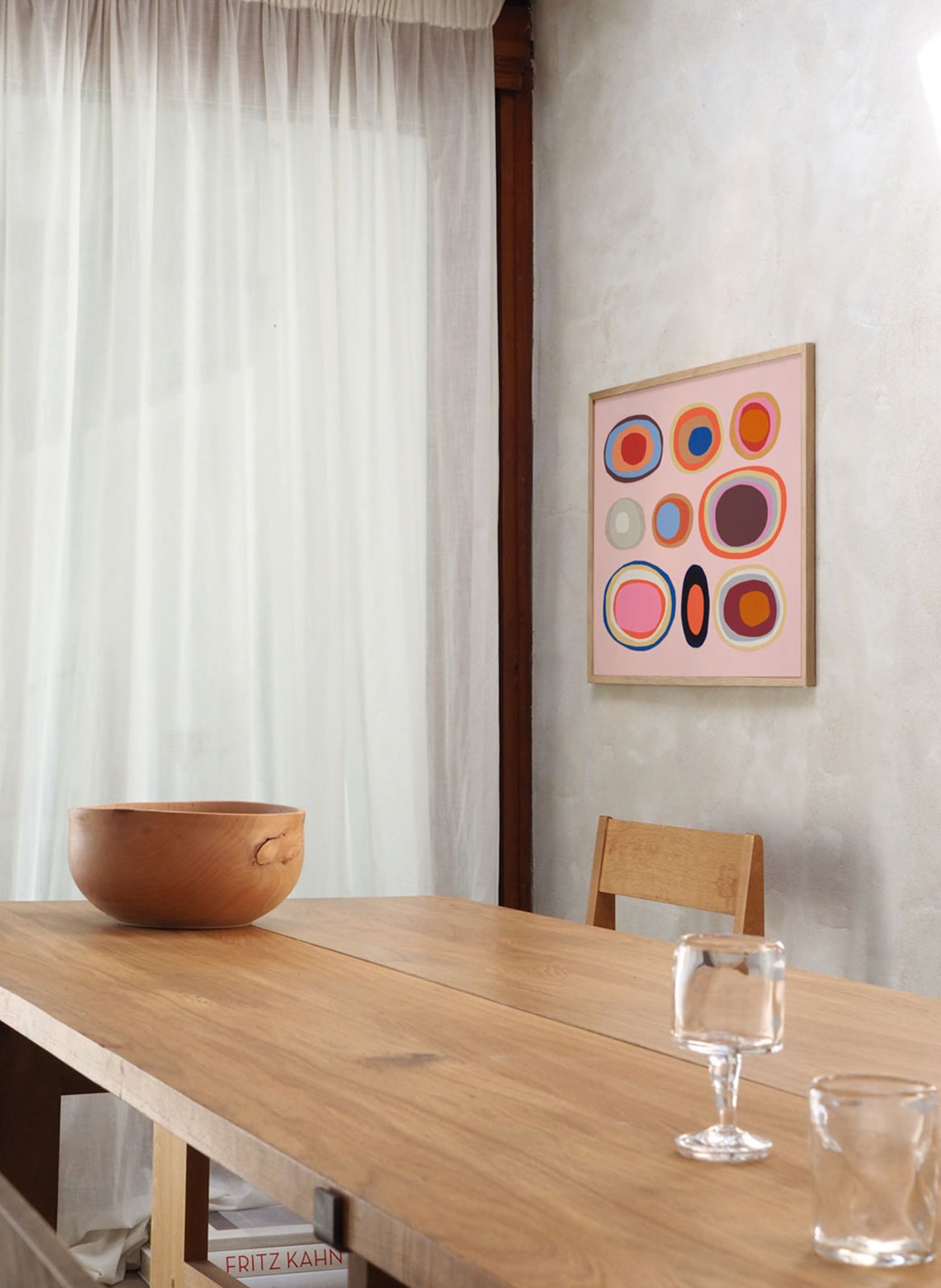 Framed colourful poster hanging above dining table by Atelier Cph