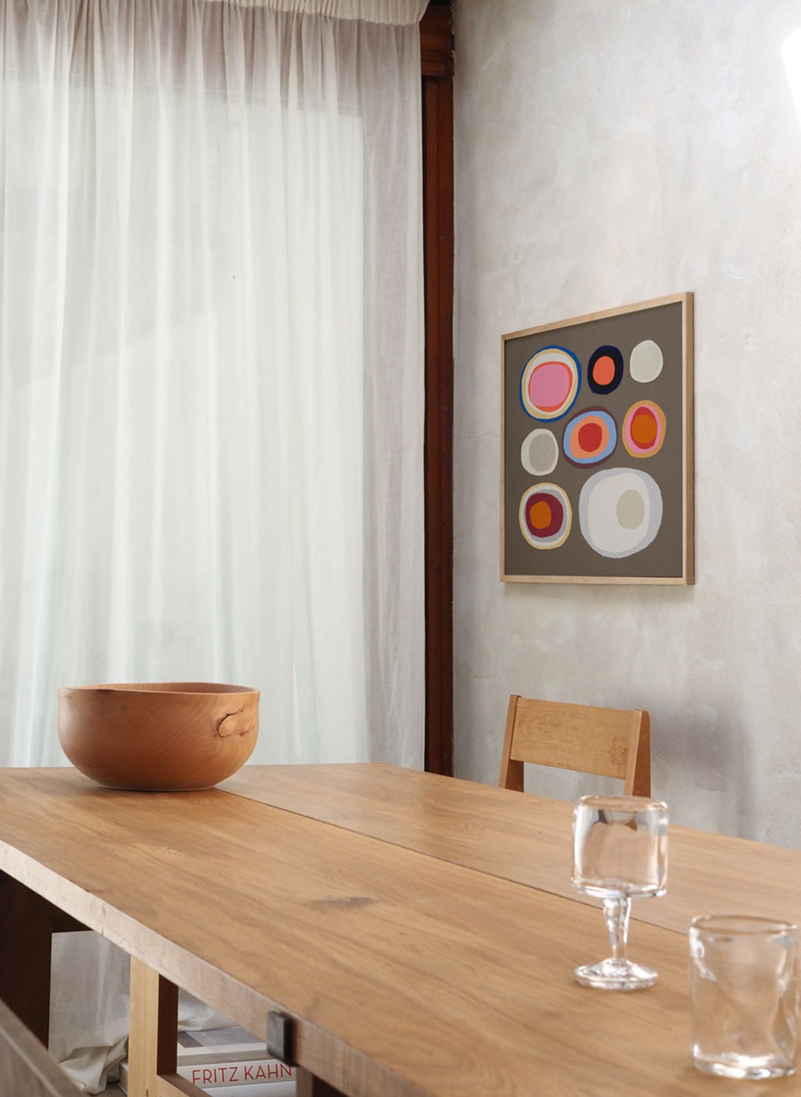 Framed colourful poster hanging above dining table by Atelier Cph