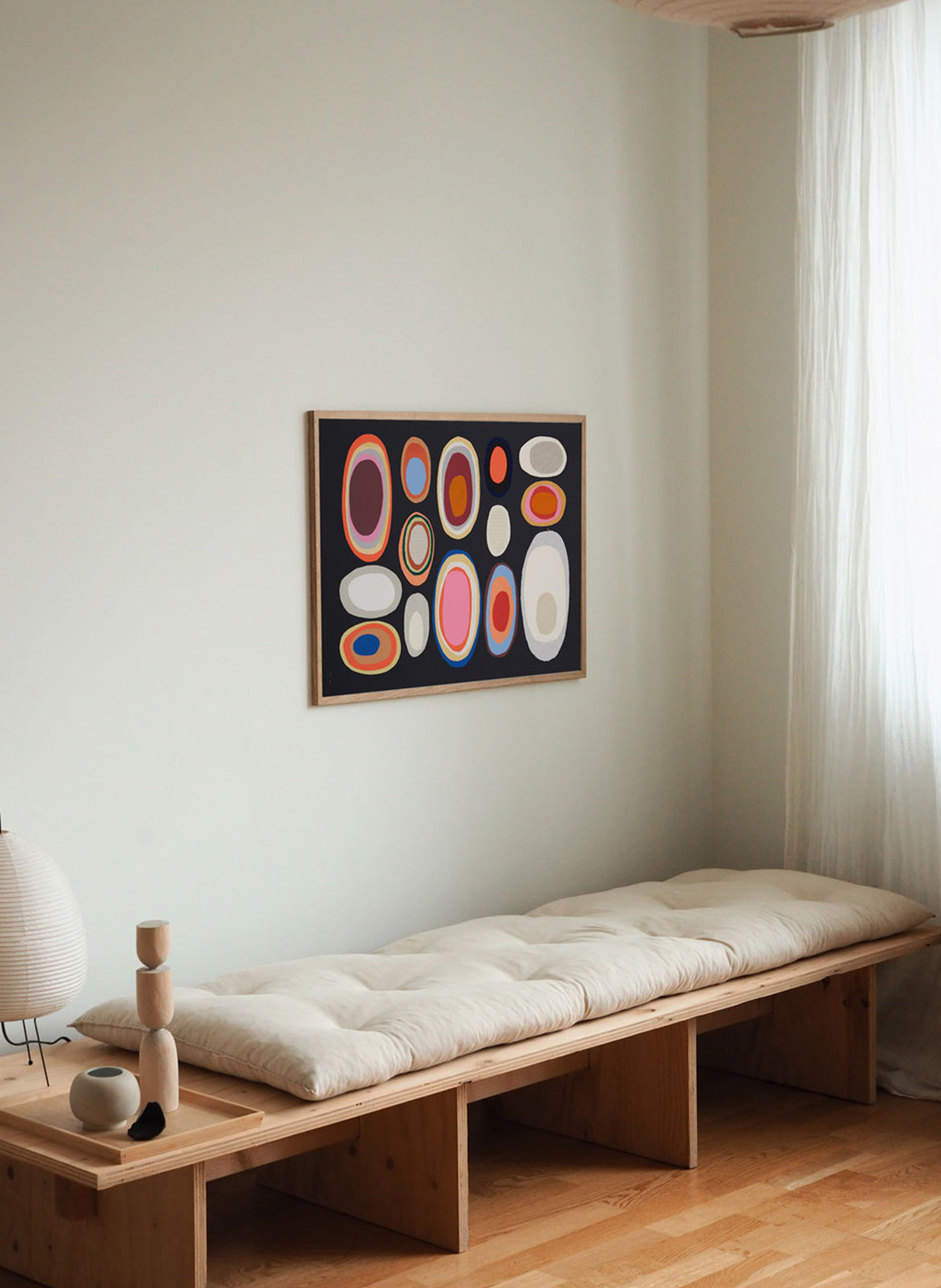 Framed colorful poster hanging above daybed by Atelier Cph