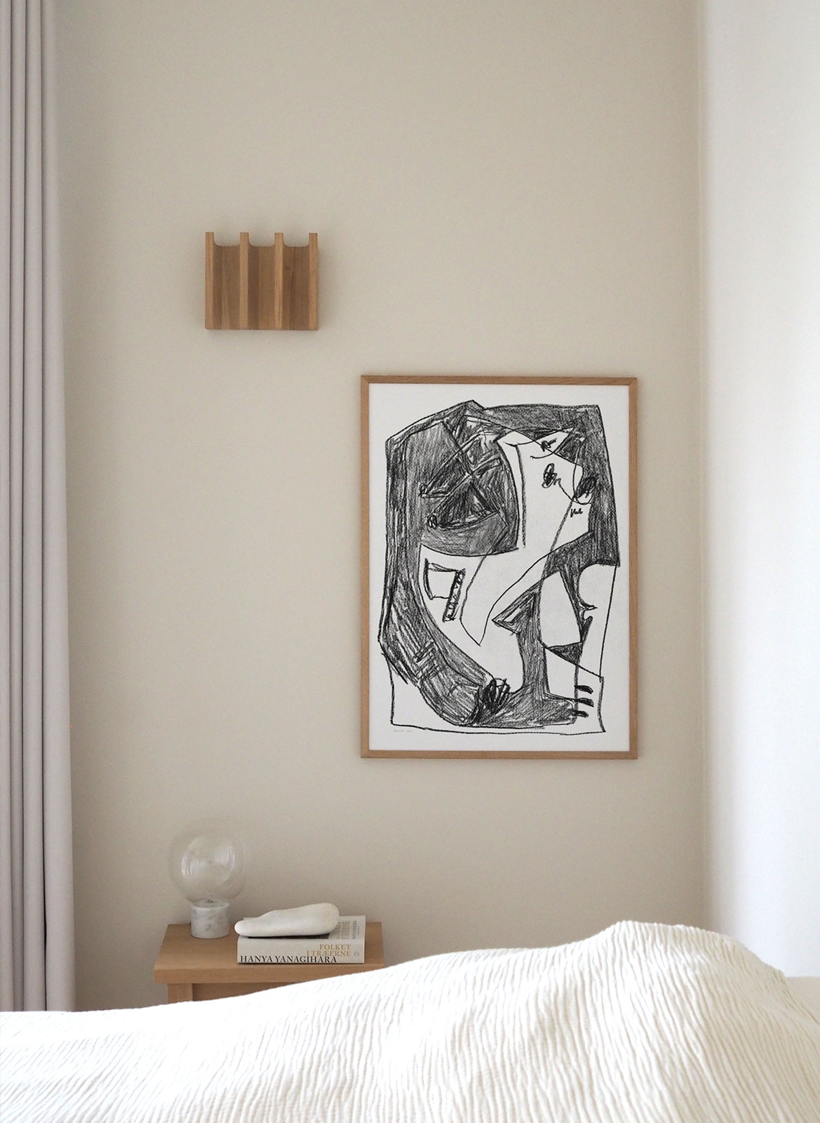 Framed minimalistic poster hanging above bed by Atelier Cph