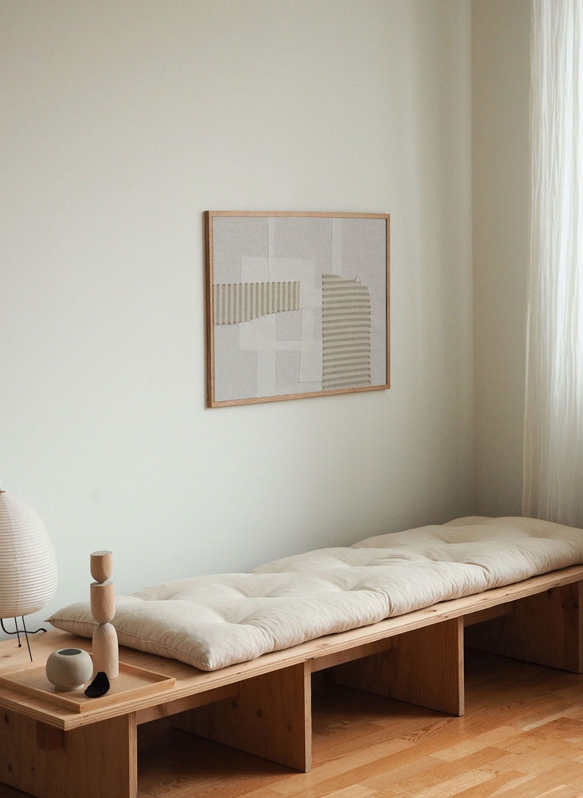 Framed black and white poster hanging above daybed by Atelier Cph
