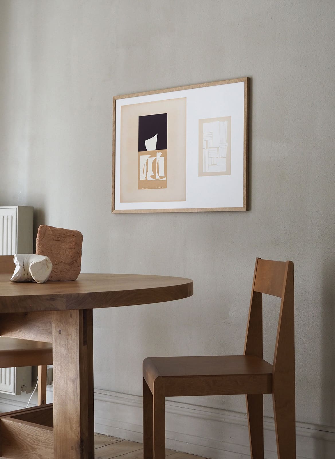 Framed minimalistic poster hanging above dining table by Atelier Cph