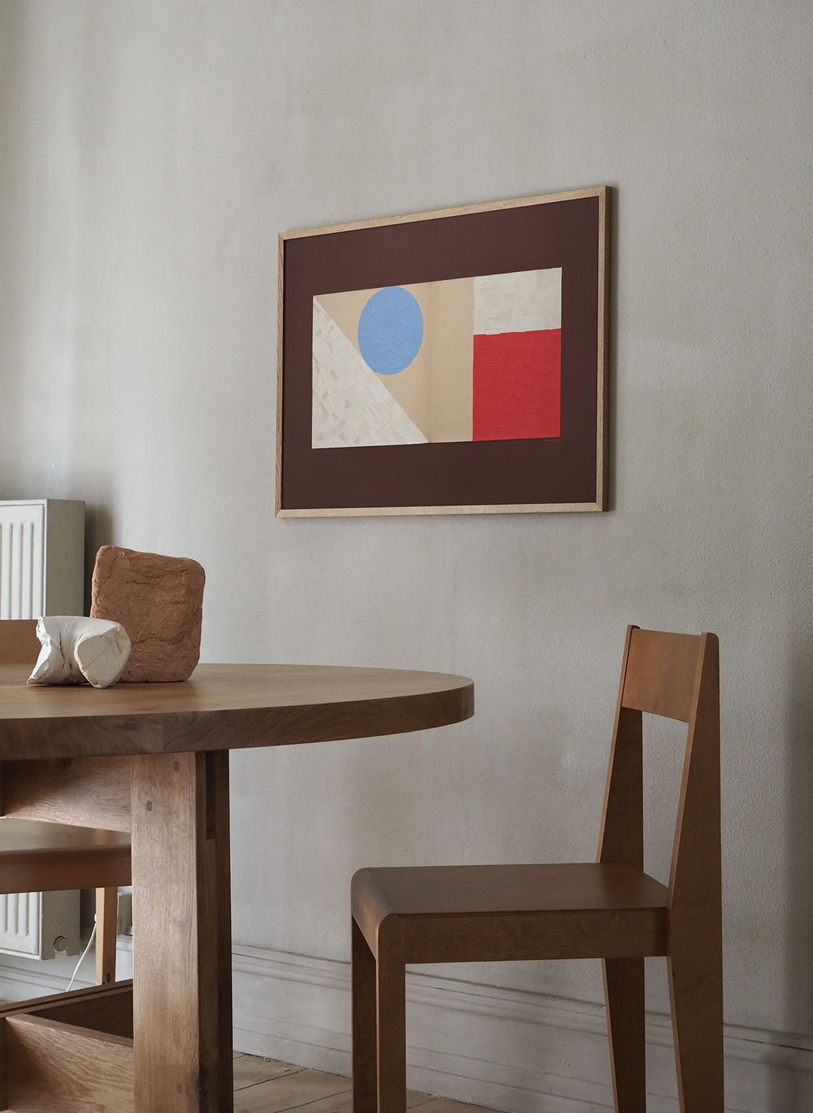   Framed colourful poster hanging above dining table by Atelier Cph