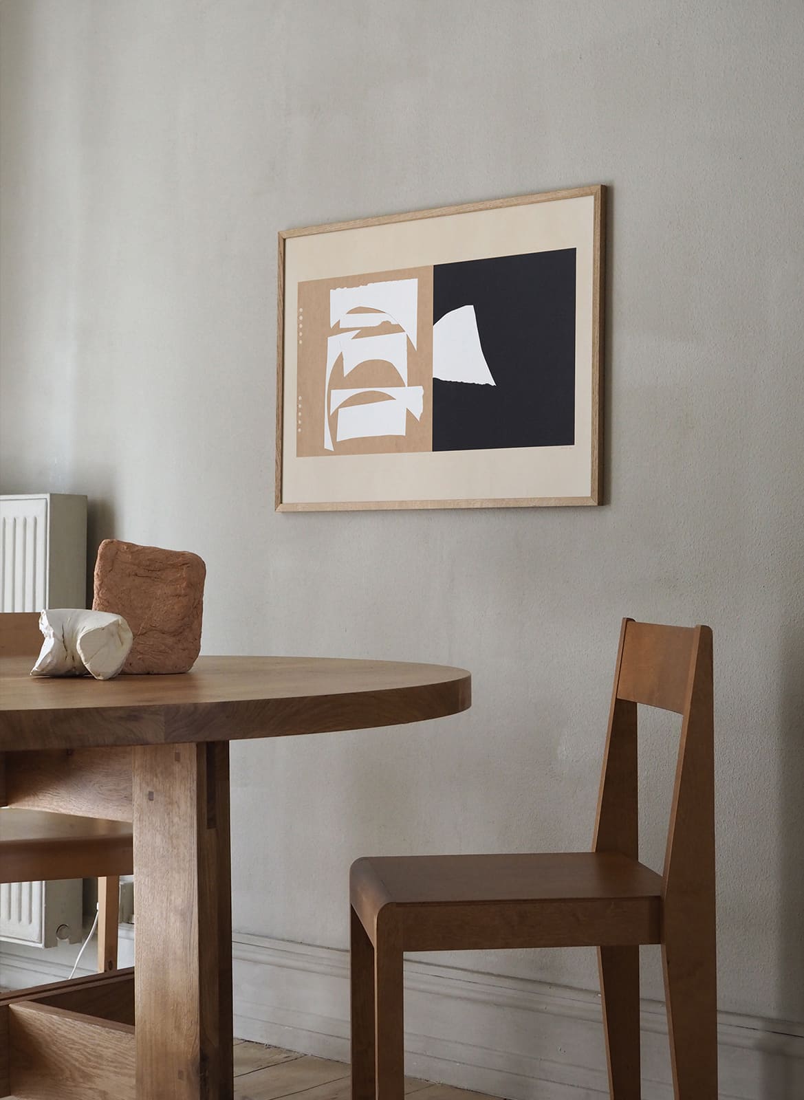 Framed minimalistic poster hanging above dining table by Atelier Cph