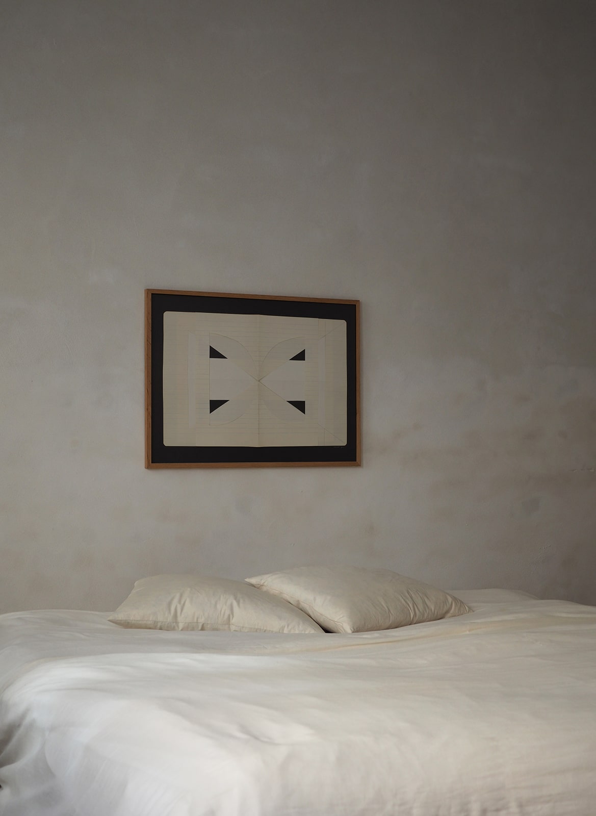 Framed art print with a paper cutout hanging above a  bed by Atelier Cph