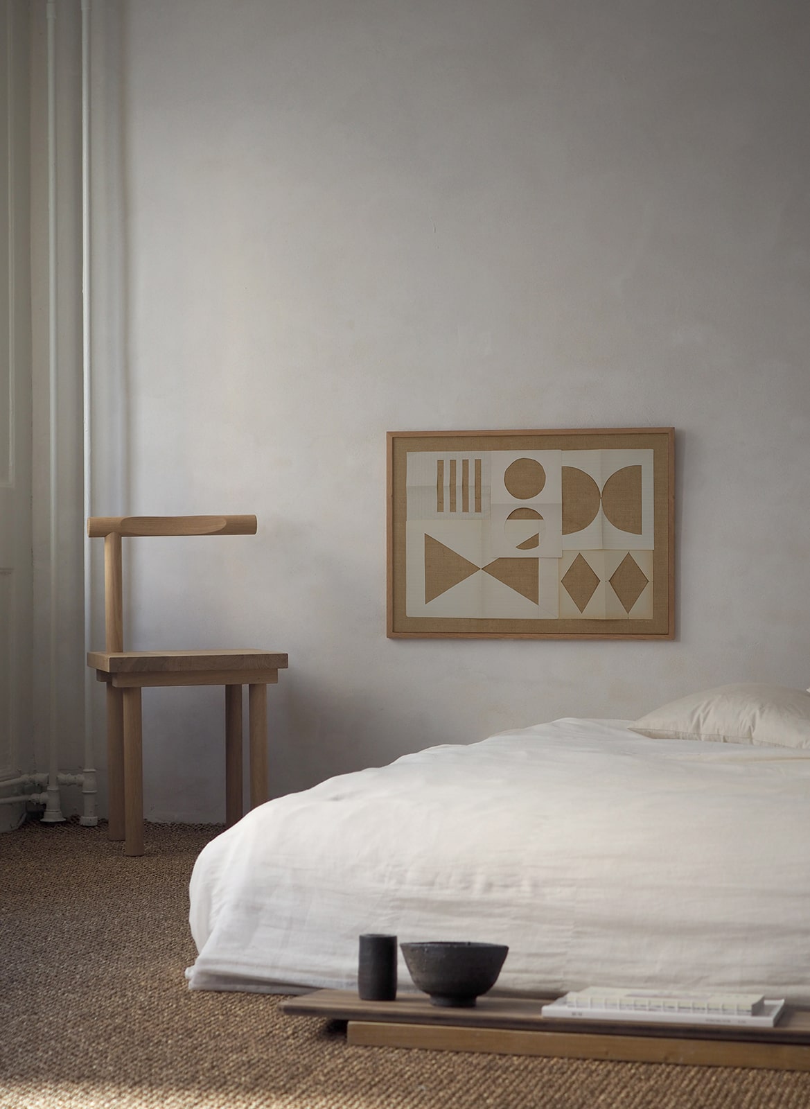 Framed art print with a paper cutout hanging above a bed by Atelier Cph