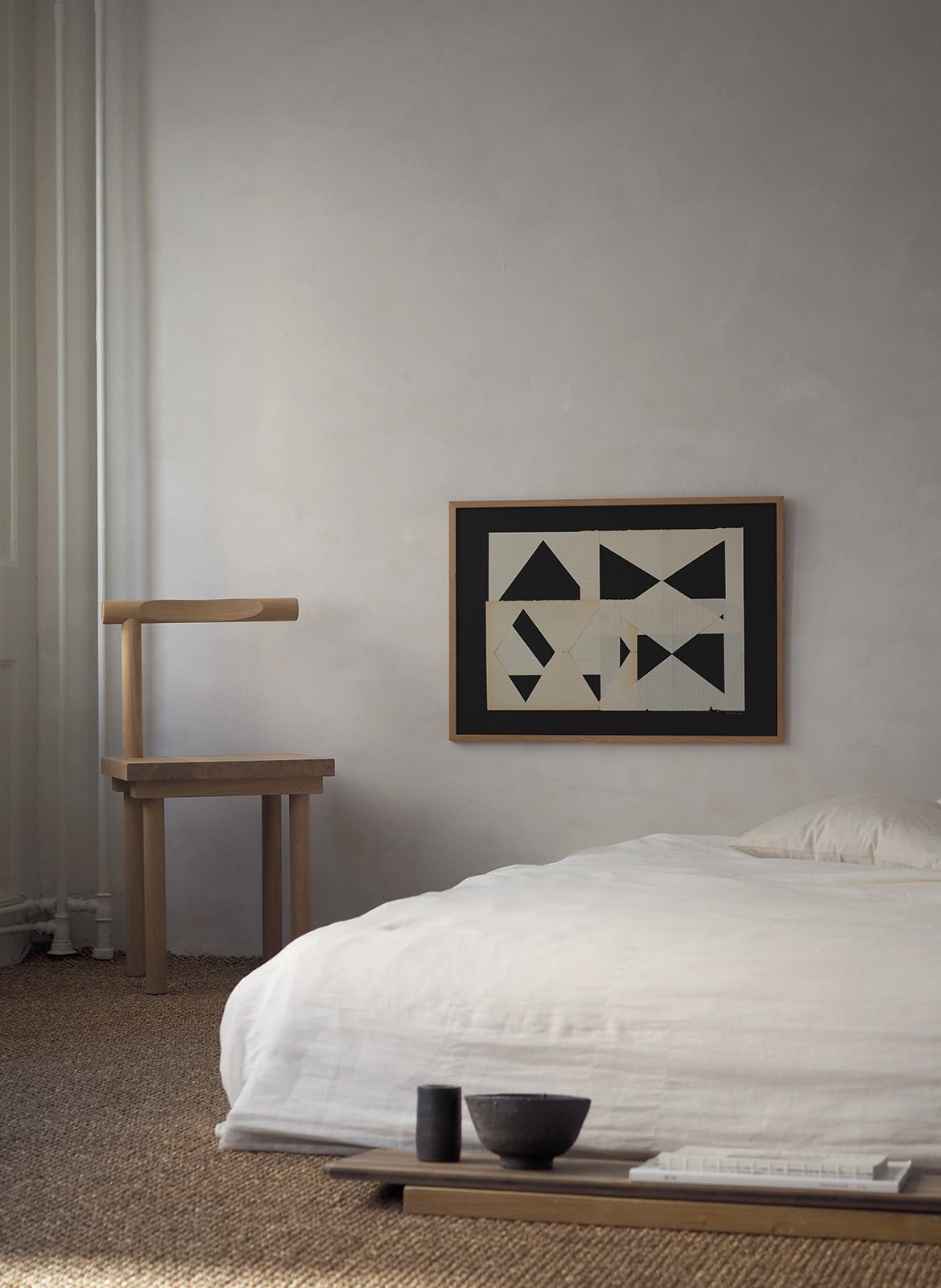 Framed art print with a paper cutout hanging above a bed by Atelier Cph