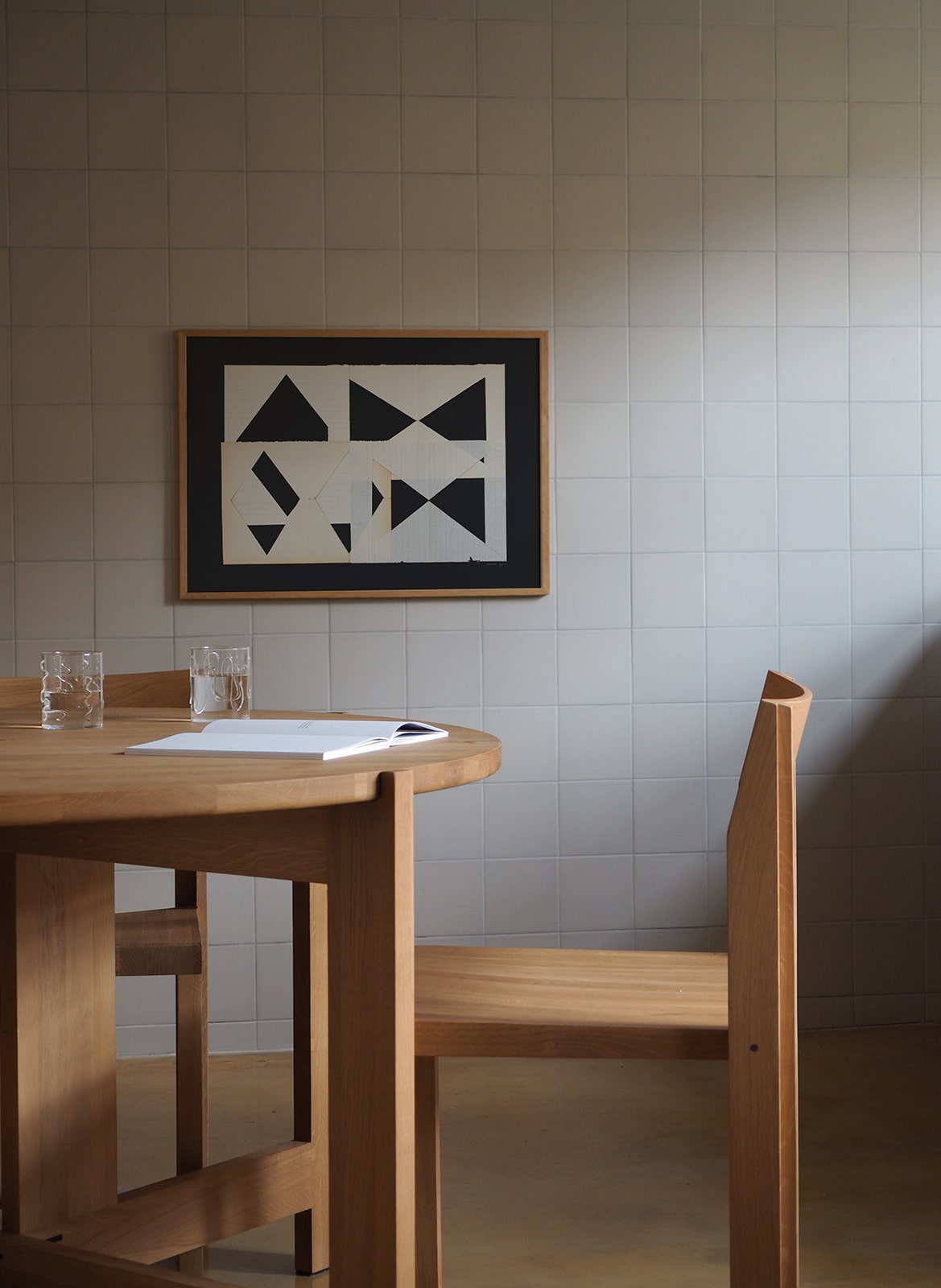 Framed art print with a paper cutout hanging above a table by Atelier Cph