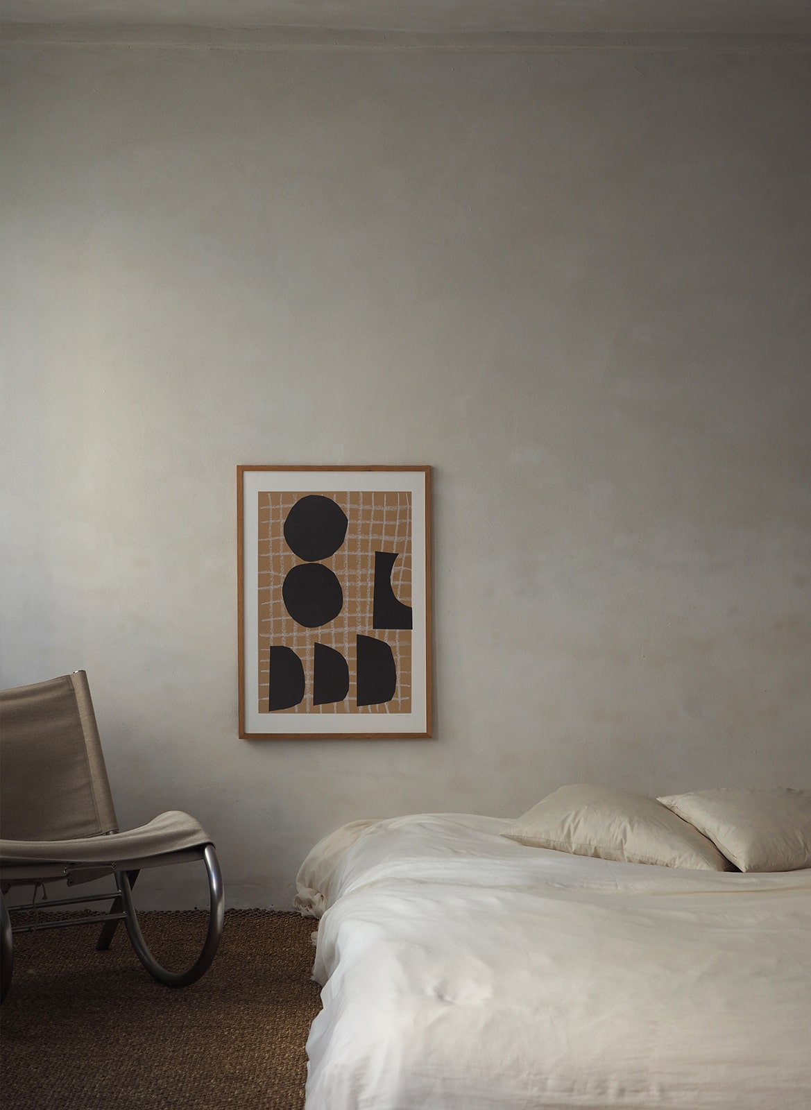 Framed poster with circles hanging above a bed by Atelier Cph