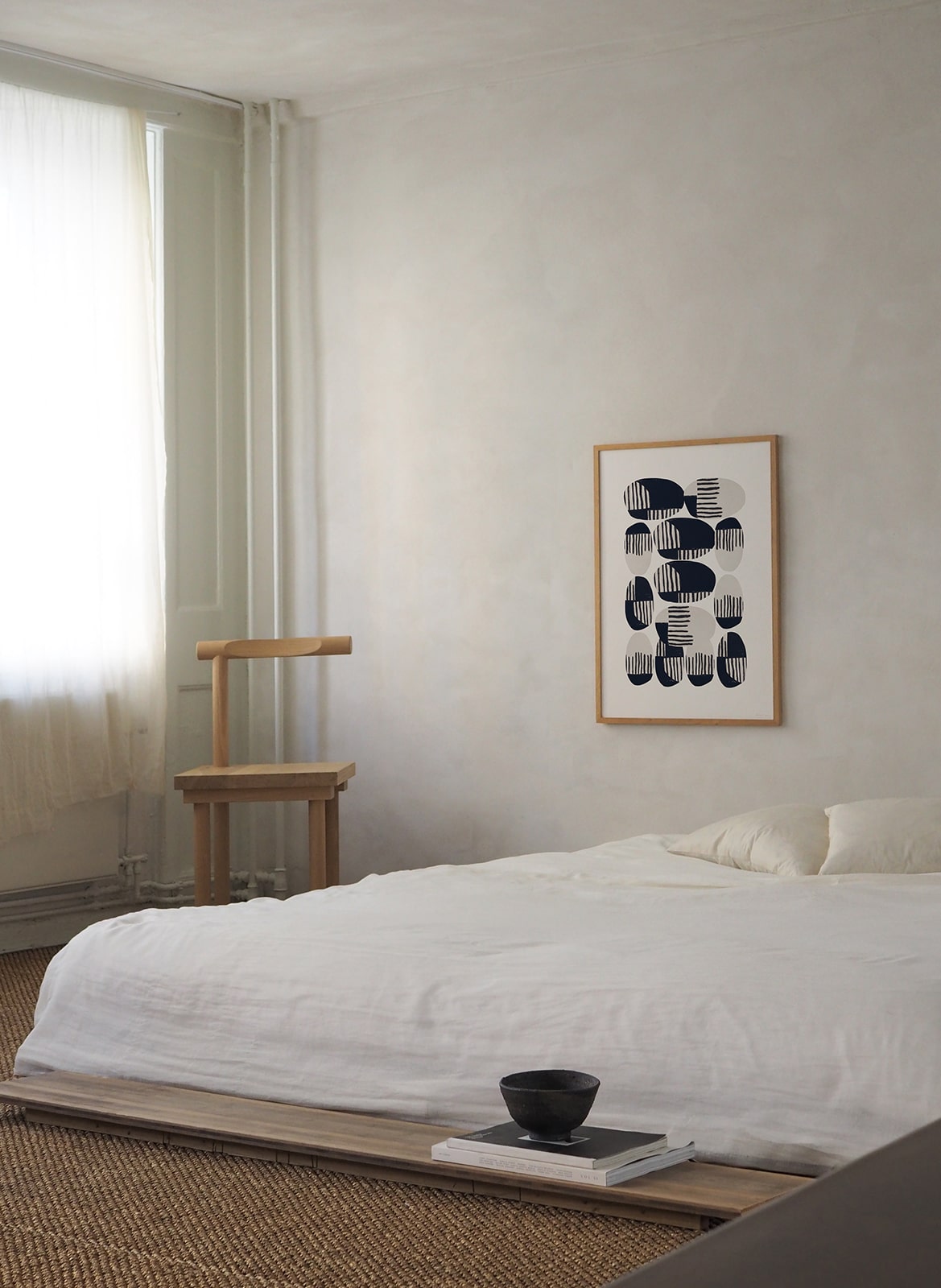 Framed minimalistic poster hanging above a bed by Atelier Cph