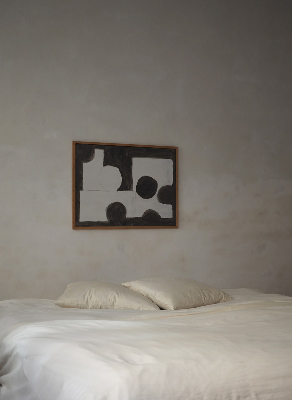 Framed minimalistic poster hanging above a bed by Atelier Cph