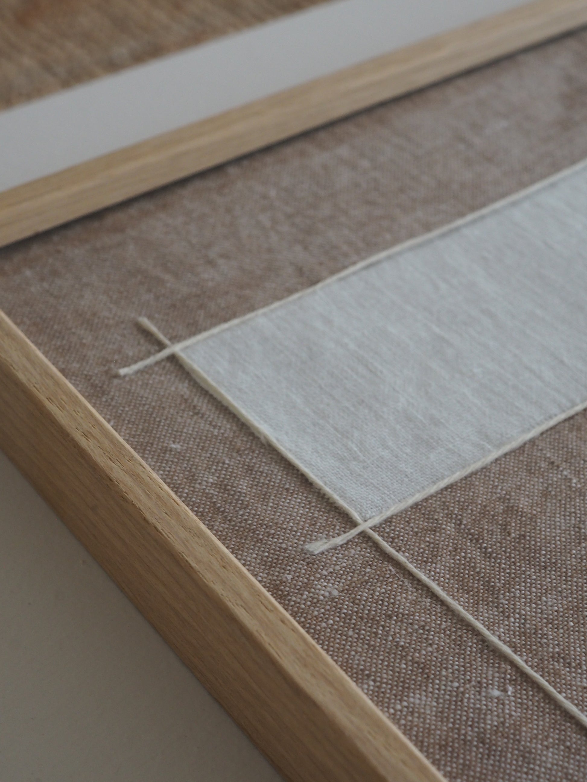 details of artwork made from natural linen with structured graphic lines in neutral tones.
