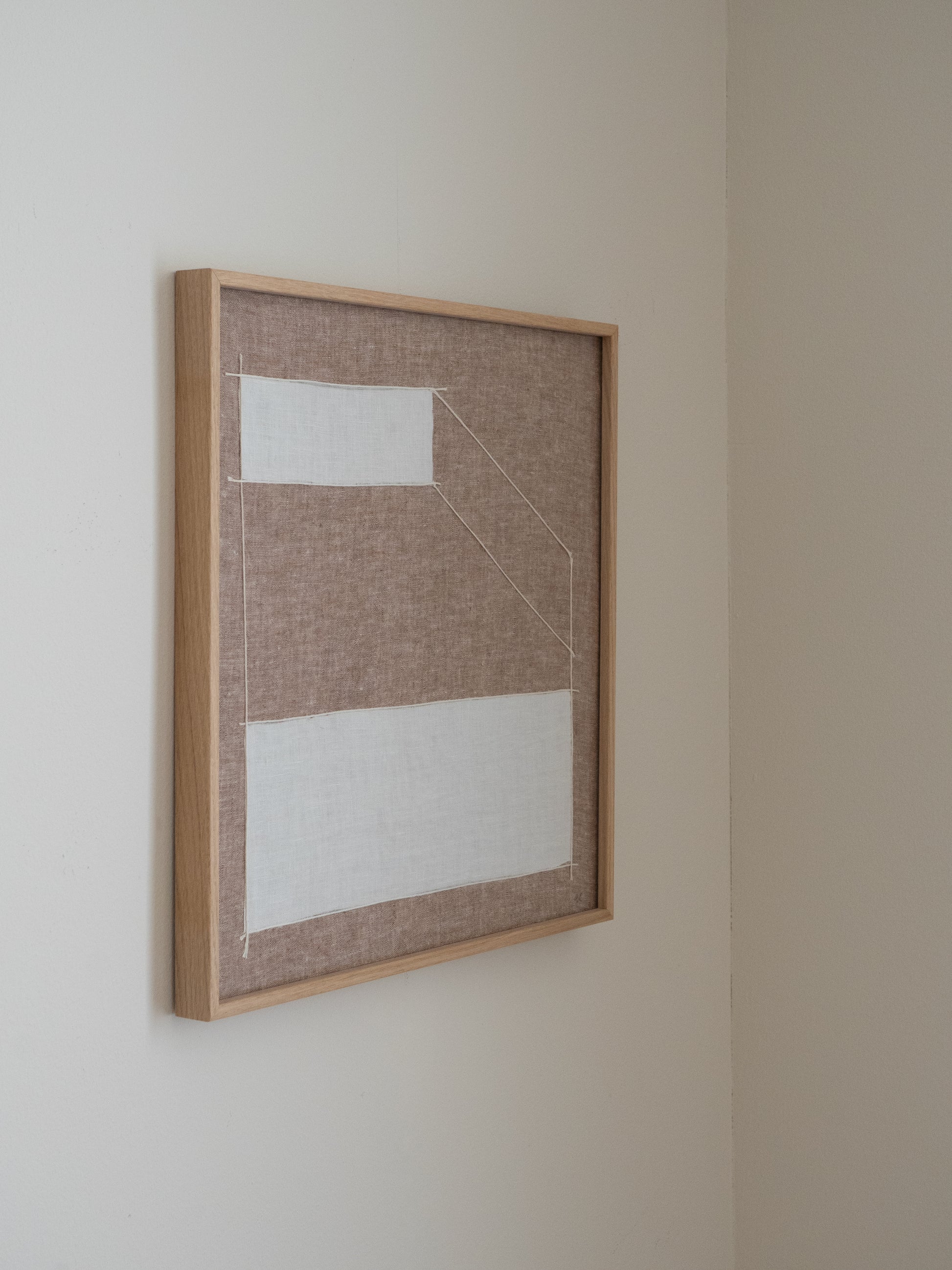 Abstract textile artwork made from natural linen with structured graphic lines in neutral tones hanging on wall