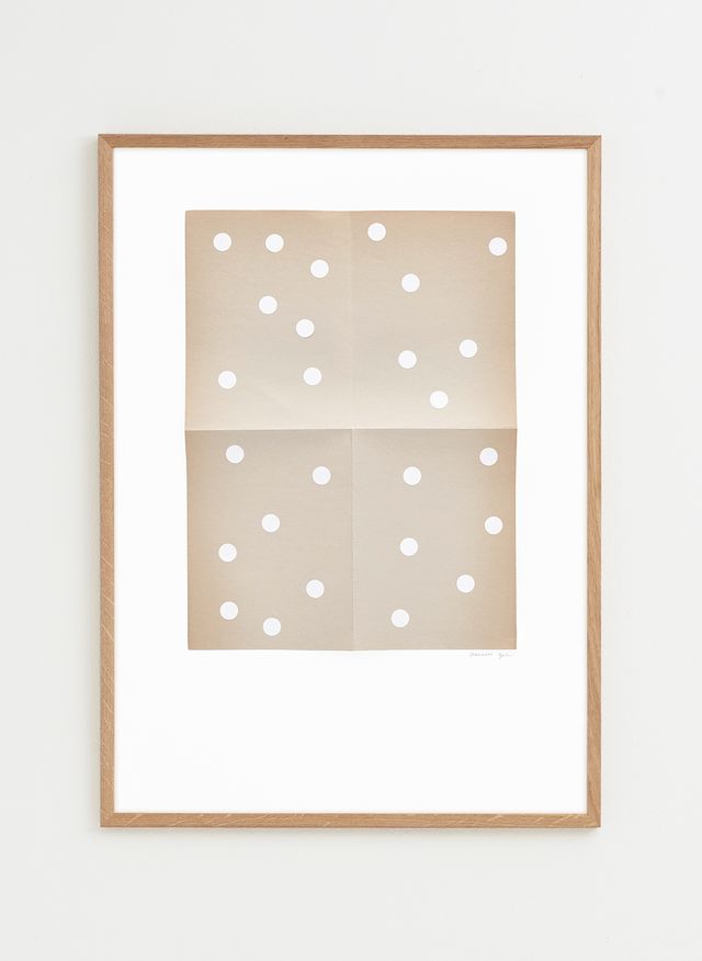 Framed artwork with a beige background and white polka dots 