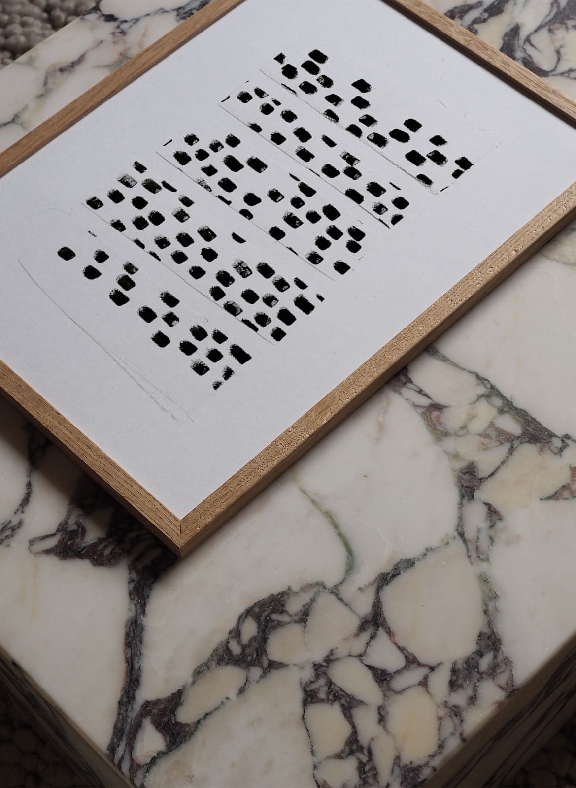 White poster with black dots laying on a marble table