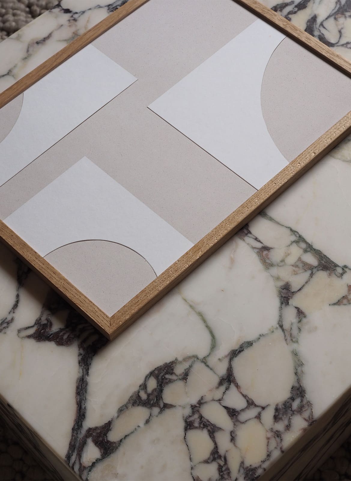 Framed white on white poster laying on a marble table by Atelier Cph