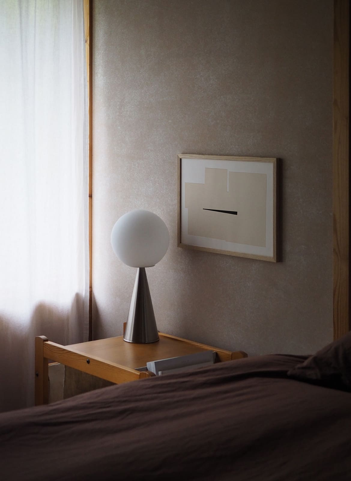 Framed minimalistic poster hanging in a bedroom by atelier cph